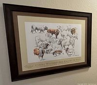 Framed poster on wall showing multiple cow illustrations and signature by T.D. Kelsey