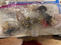 Two clear zipper bags containing assorted costume jewelry including metal rings, earrings, and fabric/plastic flower pins.