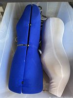 Top view of two dress form torsos inside a large clear plastic tub, one blue adjustable and one white static.