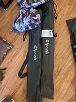 Two Glymnis branded carry bags, one black and one blue camouflage pattern, for trekking poles.