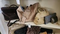 Multiple purses, bags and clutches on a shelf showing colors, materials and styles