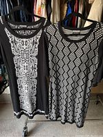 Two black and white dresses displayed side by side on hangers, showing different patterns and fabric textures.