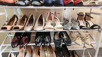 Two shelves holding 9 pairs of women's shoes in size 10 and 11 including high heels and loafers/slip-ons.