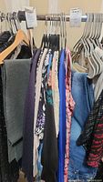 Photo showing multiple women's tops on hangers including sweaters, blouses, casual tops, and a gray scarf.