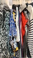 Photo showing a variety of women's tops hanging on a rack including animal print, striped, and patterned tops.