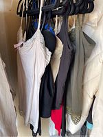 Photo of multiple women's camisoles hanging on black hangers, showing variety of colors and lace trims on straps and hems