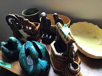 Overview of all lot items on table: swans, McCoy planter, Haeger bowl, wood carvings