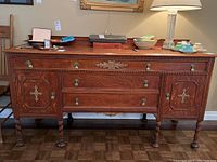 Front view of the vintage wooden sideboard cabinet showing three drawers, two side doors, brass hardware, and wood carved decorative details.