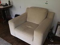 Front view of beige fabric covered armchair showing cushioned seat, backrest, and armrests.