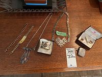 Full lot overview on wooden surface showing all jewelry items including chains, Mexican 925 silver necklace, cuff links, tie clip, and silver lighter case.