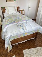 Full view of twin bed assembled with linens and mattress