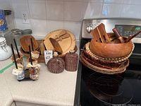 Overview of wooden bowls, serving plates, utensils, basket trays, cork bottles, napkin rings on kitchen counter