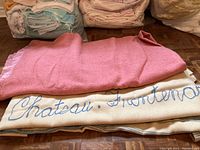 Two folded blankets, one pink Kenwood Wool and one beige embroidered with "Chateau Frontenac".