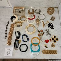 Overall lot arranged on marble surface showing all bracelets, brooches and shoe clips.