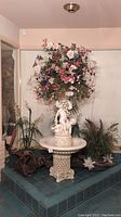 Full view of cherub fountain with floral arrangement and driftwood accents