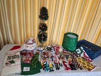 Overall display of lot showing all items for sale including punch bowl set, tree, ornaments, felt dolls, packaging, and textiles.