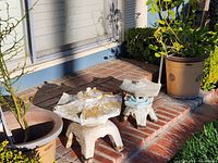 Two weathered concrete pagoda-style garden ornaments with lichen on brick step