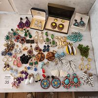 Overview of 35 pairs of assorted clip-on earrings displayed on marble surface