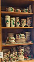 Overall shelves displaying multiple Franciscan Apple pieces including vases, mugs, bowls and plates