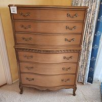Front view of nine-drawer dresser showing carved aprons and brass handles