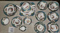 Overhead view of teapot on tray, serving plate, six cups with saucers, sugar bowl and creamer.