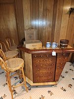 Front view of vinyl padded faux wood bar with accessories on top