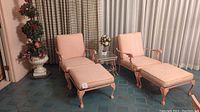Two wrought iron chairs with pink cushions and two matching ottomans