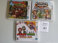 Photo of three Nintendo 3DS games: Mario & Luigi Paper Jam, Donkey Kong Country Returns 3D, and Harvest Moon 3D: A Tale of Two Towns, all in original cases with cover art visible.