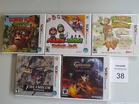 Five Nintendo 3DS game cases displayed on tabletop: Donkey Kong Country Returns 3D, Mario & Luigi: Paper Jam, Story of Seasons, Fire Emblem Awakening, Castlevania: Mirror of Fate