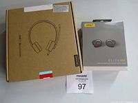 Photo of two boxed audio items: Lenovo wired headphones in brown box and Jabra Elite 85t wireless earbuds in retail packaging.