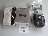 Photo showing the Jabra Elite 85t wireless earbuds box, Escape wireless earphones box, and Roots small camera bag in a plastic bag along with a product manual.