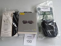 Photo shows three items: white Escape wireless earbuds in original box, Jabra Elite 85t earbuds in gray box, and Roots small black camera bag sealed in plastic packaging.