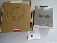 Photo of Lenovo 100 Stereo Analog Headphones box next to Jabra Elite 85t Earbuds box, showing overall packaging and branding.