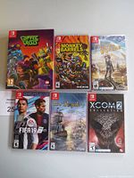 Photo displaying six Nintendo Switch game cases arranged in two rows of three, titles clearly visible.
