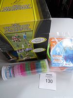 Photo showing boxed 2-in-1 lawn darts and bocce set, tube of badminton shuttlecocks, and sealed package of colorful pool rings.