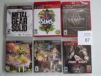 Photo showing six new, shrink-wrapped PS3 game cases arranged in two rows of three, featuring Metal Gear Solid, The Sims 3, Skyrim Special Edition, two Atelier games, and Fight Night Champion.