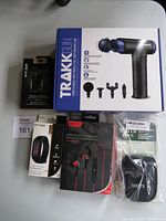 Photo of Trakk massage gun box, Escape wireless earbuds, Roots camera pouch, Massaid fitness tracker box, and Escape wireless spot earbuds package.