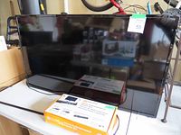 Flat screen TV with UltraLink Home Entertainment Starter Kit box placed on table in front.