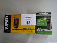 Photo showing two boxed items: Viper 2-Way Remote Start System in yellow and black box, model 4305V1; Alcohawk Ultra Slim Breathalyzer in black and green box.