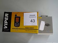 Photo of the Viper 2-way remote start system box and Jabra Elite 85t earbuds box side by side on a white surface with a MaxSold auction lot number 43 label visible.