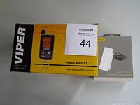 Photo of Viper Model 4305V1 2-Way Remote Start System box in yellow and black, alongside Jabra Elite 85t earbuds box in gray.