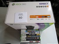 Xbox 360 Kinect box showing the console and Kinect branding with 9 Xbox 360 game cases stacked on top.