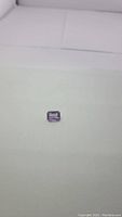 Natural purple amethyst gemstone photographed on a white surface showing emerald cut shape and size.