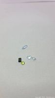Five natural gemstones including aquamarine, peridot, and tourmaline on white background.