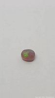 Loose natural chocolate Ethiopian opal gemstone photographed on plain background to show color and size.