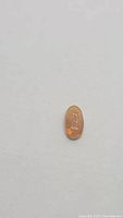 Close-up of an oval cabochon Ethiopian opal with visible orange flash and translucent butterscotch color under diffused light.