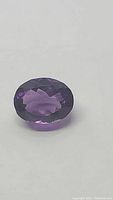 Close-up of the deep purple oval-cut amethyst gemstone showing faceting and color