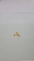 Four small caramel colored Mexican opal gemstones placed on white background showing their size and color.