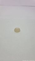 Natural pearl white moonstone cabochon gemstone placed on a white background, showing the smooth oval shape and translucent pearl white color.