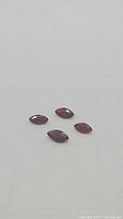 Four marquis cut natural untreated blood red rubies arranged on a white surface, showing the shape, color, and size scale.